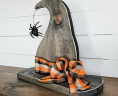 an orange and black bow sitting on top of a piece of wood next to a spider