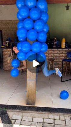 a woman is playing with blue balloons on a pole