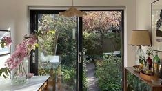 a room that has some flowers in vases on the table and an open glass door