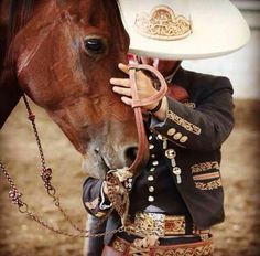 a man in uniform is petting a horse's bridle while wearing a cowboy hat