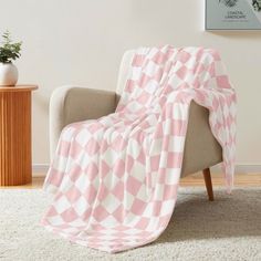 a pink and white blanket sitting on top of a chair next to a potted plant