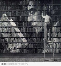 a man standing on top of a ladder in front of a book shelf filled with books