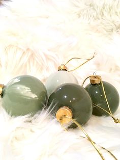 three green glass ornaments sitting on top of a white fur covered floor next to each other