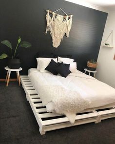 a white bed sitting in a bedroom on top of a hard wood floor next to a potted plant