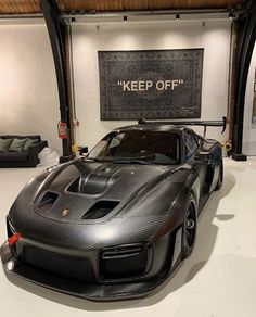 a black sports car parked in a garage next to a sign that says keep off