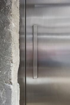 a stainless steel door is next to a concrete wall and cement block on the ground