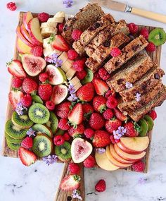 a wooden platter filled with sliced up fruit and nutritious meatloaf