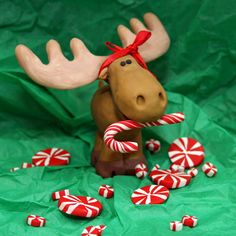 a stuffed moose with candy canes and candies on a green sheeted surface