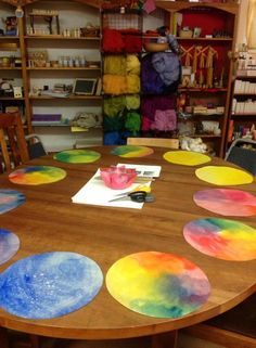 a wooden table topped with lots of different colored paper plates on top of each other