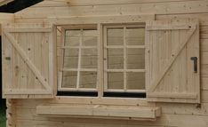 a small wooden house with windows and shutters