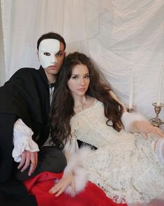 a man and woman dressed up as dracula and the girl in white is wearing a mask