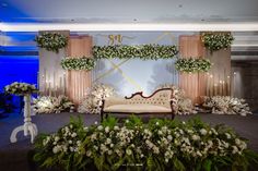 a couch sitting on top of a carpet covered floor next to flowers and greenery