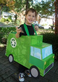 a young boy is holding up a green truck cardboard box that he made out of