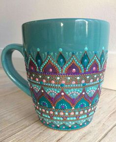 a teal colored coffee cup sitting on top of a wooden table