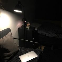 a laptop computer sitting on top of a table next to a lamp in a dark room