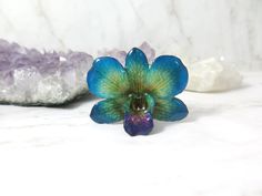 a glass flower sitting on top of a table next to crystals