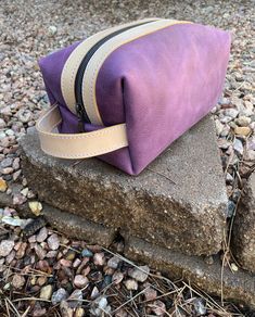 This gorgeous purple make up bag/Dopp kit is made from 100% US Leather. These make a great gift when you don't know what to buy. All women will use this for traveling, makeup, jewelry, shaving, etc! This Dopp kit measures 8"x6"x6" and is fully lined with a pretty Aztec patterned duck cloth. A handle on one side and a pull tab on the other allow ease for zipping open and shut, and for carrying.  Handle, tab, and zipper sides are 100% US veg tan leather.  This Dopp bag is 100% handmade! Purple Zipper Pouch Cosmetic Bag For Travel, Purple Pouch Cosmetic Bag For Travel, Purple Cosmetic Bag For Everyday Use, Handmade Purple Bags For Gifts, Handmade Purple Bags As Gifts, Purple Rectangular Travel Cosmetic Bag, Purple Rectangular Travel Pouch, Rectangular Purple Travel Pouch, Purple Pouch Bags With Zipper