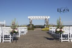 an outdoor wedding set up with white chairs and flowers