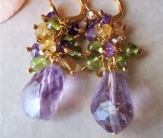 A gorgeous Aquamarine Gemstone., all one-of-a-kind natural gemstone hand-picked for its color and beauty. This lovely pair of earrings features a beautiful light amethyst Gemstone, with small clusters of amethyst, peridot and citrine gemstones. dangles on a gold lever back. Each stone may vary slightly in size and shape. Earrings measures 1.75 inches in length. Earrings are light weight and sway gracefully as you move about your day. These gorgeous cluster earrings are unique, feminine and eye-c Statement Chandelier, Light Amethyst, Earrings Purple, Making Earrings, Diy Making, Yellow Citrine, Pretty Necklaces, Green Peridot, Citrine Gemstone