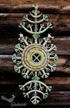 an intricately designed wall hanging on the side of a wooden building, with green and yellow accents