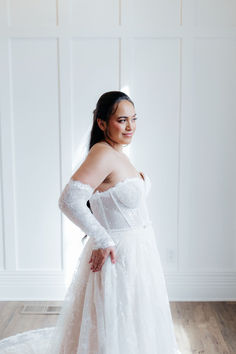 a woman in a wedding dress posing for the camera with her hands on her hips