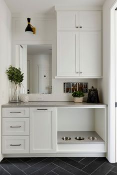 a kitchen with white cabinets and black tile flooring