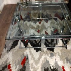 a glass coffee table sitting on top of a rug