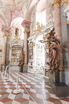 the interior of a library with statues and bookshelves on either side of it