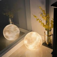 two round lights sitting on top of a counter next to a vase