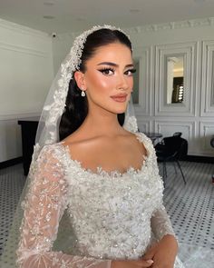 a woman in a wedding dress with a veil on her head and wearing a tiara