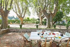 an outdoor dining area with tables and chairs in the middle of a courtyard surrounded by trees