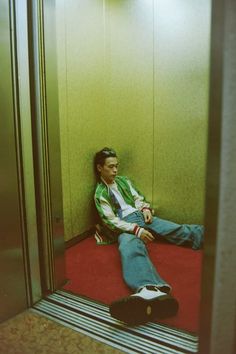 a man sitting on the floor in an elevator with his feet propped up against the wall