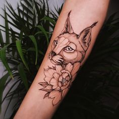 a black and white photo of a fox with flowers on it's arm, next to a plant