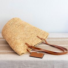 a straw bag sitting on top of a table next to a brown leather keychain