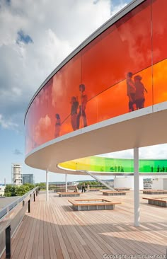 an image of people walking on the boardwalk in front of a colorful wall and bench area