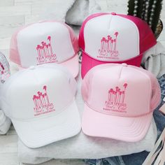 four pink and white hats sitting on top of a pile of clothing next to each other