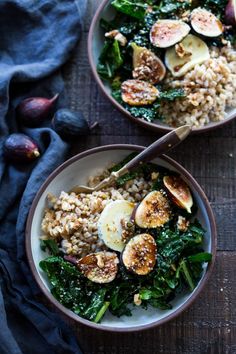 two bowls filled with rice, greens and figs on top of a wooden table