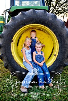 two children are sitting in the front of a tractor with their mom and dad on it