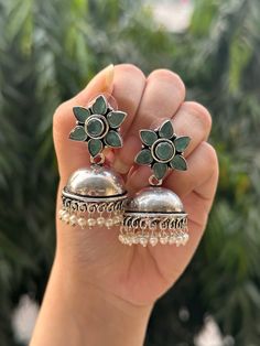 These high quality German silver earrings are the perfect addition to any ethnic or western look. The stone used reflects light and gives a look of mystery and allure to your outfit. These earrings will last you forever and are sure to be your go to pair! Plus they came in an adorable flower shape!  Available in 4 stunning colours, these earrings need to be in your collection!  They are limited edition and unique styles so only 1 of each is available and will not be restocked in the future, so grab yours today!  In case of any query, please feel free to reach out to us. Happy shopping! Bohemian Sterling Silver Drop Jhumkas, Sterling Silver Bohemian Jhumkas, Bohemian Silver Bridal Earrings With Latkans, Bohemian Bridal Earrings With Latkans In Silver, Bohemian Bridal Silver Earrings With Latkans, Traditional Silver Flower Earrings, Elegant Silver Jhumkas For Festival, Traditional Silver Drop Flower Earrings, Traditional Silver Flower Earrings For Festive Occasions