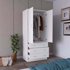 a white cabinet with drawers and clothes hanging on the wall next to a bed in a room