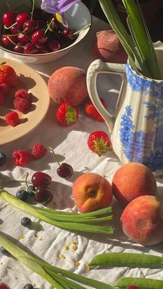 a table topped with plates and bowls filled with fruit on top of a white cloth