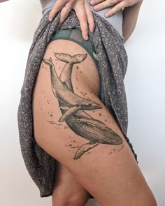 a woman's thigh with a whale tattoo on it