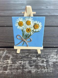 a small easel with daisies painted on it