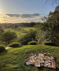 a picnic blanket is set up on the grass in front of a green golf course