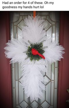 a white feather wreath with a red cardinal on it's front door hanger