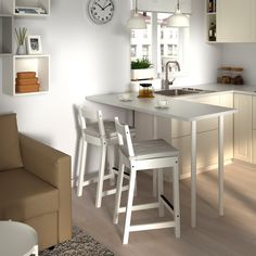 two stools sit in front of a kitchen counter with a clock on the wall