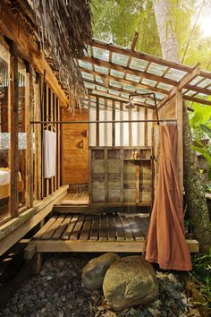 an outdoor shower in the woods with rocks and plants around it, next to a bed