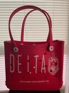 a red delta bag sitting on top of a table next to a window with blinds