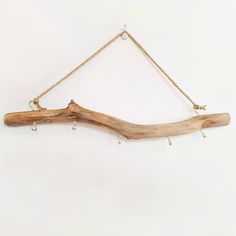 a piece of driftwood hanging from a rope on a white wall with beads attached to it