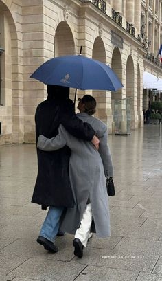 two people walking in the rain with an umbrella over their heads and one person holding onto another